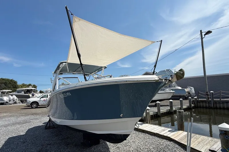 Slide: The Image of 2025 Edgewater 248CX Crossover boat with canopy, docked under clear blue sky. - 33