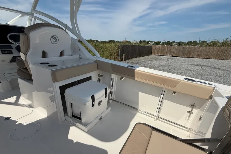 Slide: The Image of 2025 Edgewater 248CX Crossover boat interior with seating and storage, under a clear sky. - 9