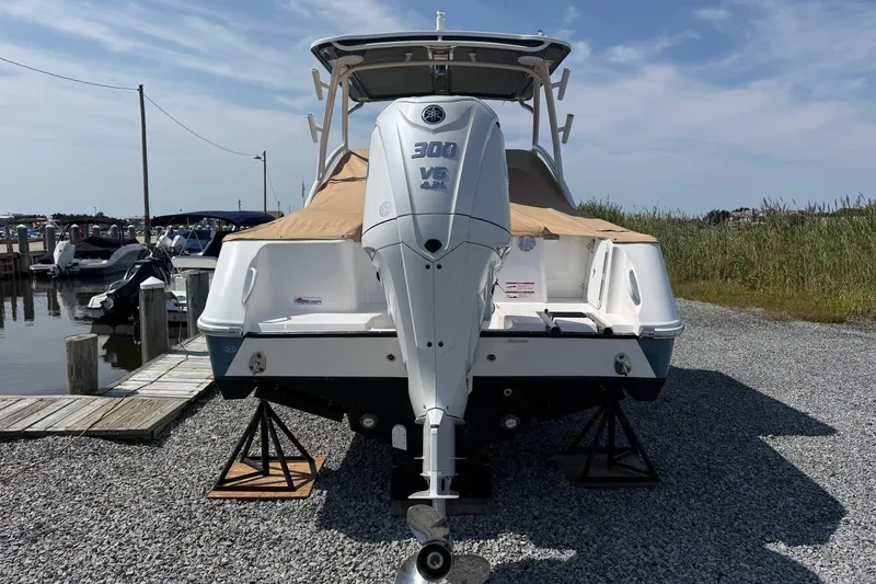 Slide: The Image of 2025 Edgewater 248CX Crossover boat with powerful 300 V6 engine, docked on gravel. - 2