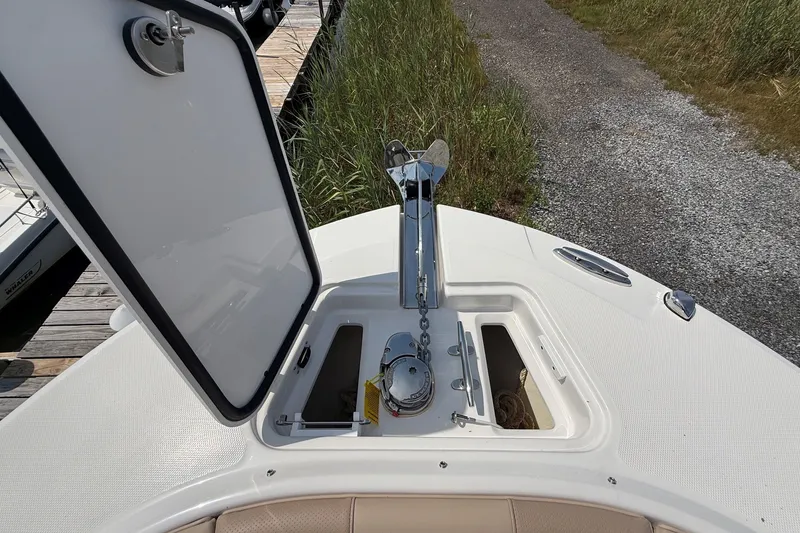 Slide: The Image of 2025 Edgewater 248CX Crossover boat anchor compartment with open hatch, dockside view. - 31