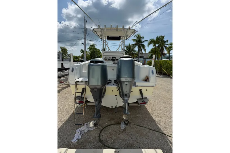 Slide: The Image of 2006 Sailfish 2360 CC boat with dual outboard motors, parked on gravel. - 5