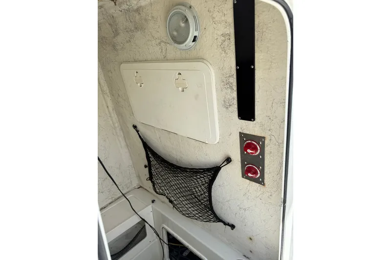 Slide: The Image of Interior of 2006 Sailfish 2360 CC boat with storage net and control switches. - 11
