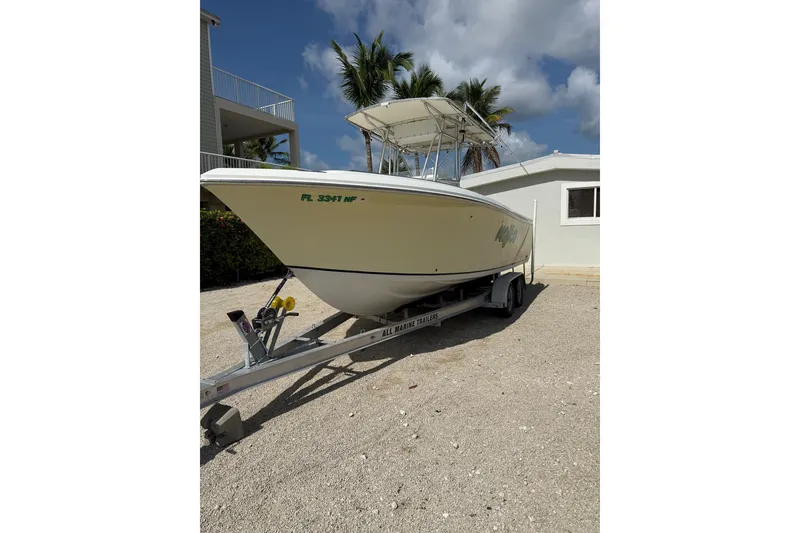 The Image of 2006 Sailfish 2360 CC boat on trailer, parked near a house under a sunny sky. - 1