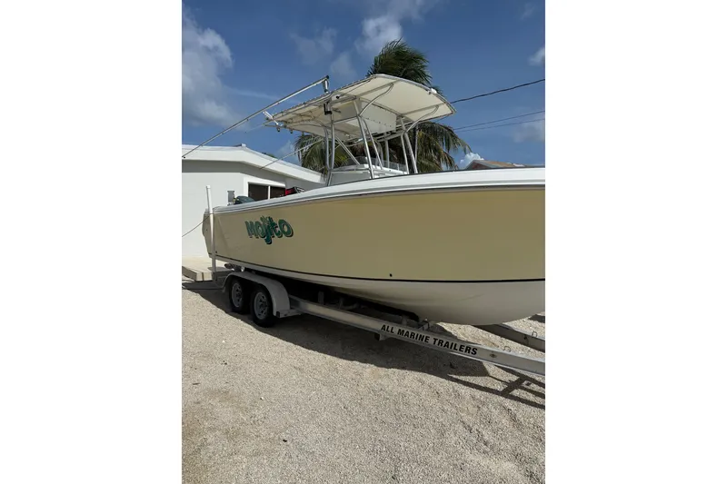 Slide: The Image of 2006 Sailfish 2360 CC boat on trailer, parked near a white building. - 3