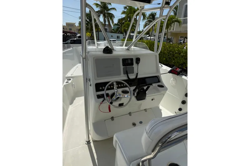 Slide: The Image of 2006 Sailfish 2360 CC boat console with steering wheel and controls, surrounded by palm trees. - 14