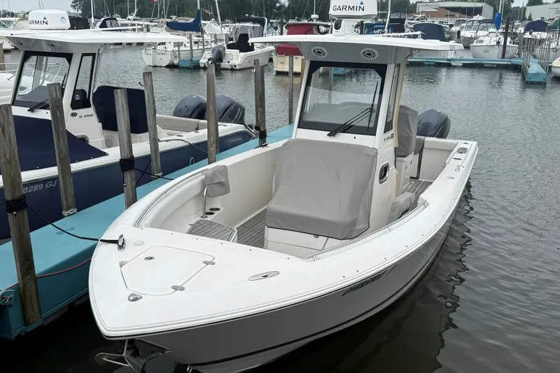 The Image of 2021 Pursuit S 268 Sport boat docked in a marina, surrounded by other vessels. - 0