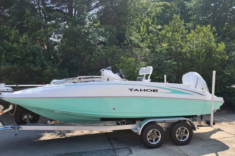 Slide: The Image of 2026 Tahoe 2150 CC boat on trailer, parked outdoors with lush greenery background. - 1