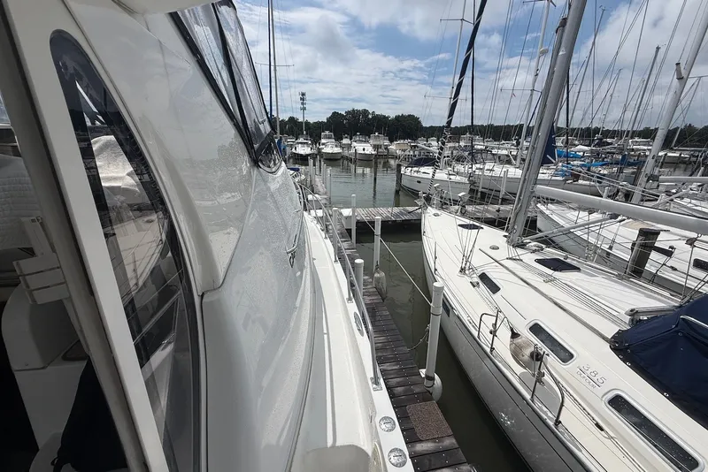 Slide: The Image of 2000 Carver 396 Motor Yacht docked at marina with sailboats under cloudy sky. - 6