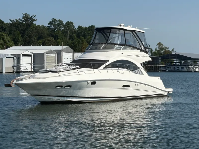 The Image of 2008 Sea Ray 47 Sedan Bridge on calm water near a marina. - 0