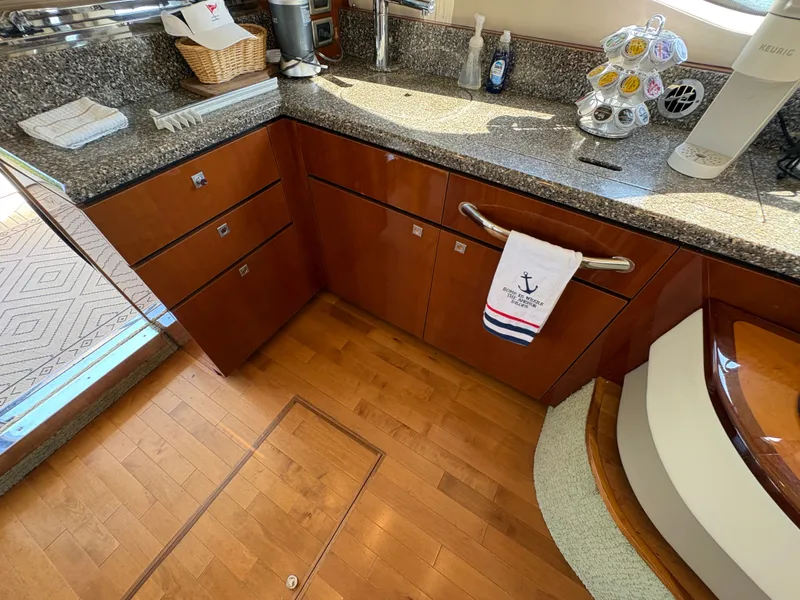 Slide: The Image of The 2008 Sea Ray 47 Sedan Bridge kitchen features an elegant countertop, wooden floors, and cabinets. - 43