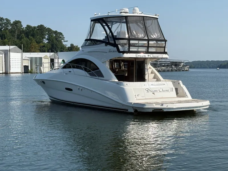Slide: The Image of A 2008 Sea Ray 47 Sedan Bridge on calm water, surrounded by trees and buildings. - 4