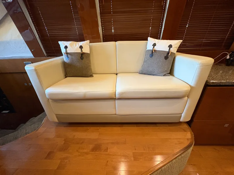 Slide: The Image of A sleek cream-colored sofa with two cushions sits on a wooden floor in a boat. - 41
