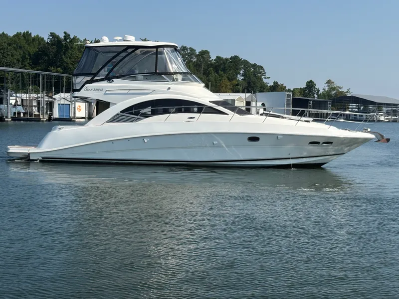 Slide: The Image of A 2008 Sea Ray 47 Sedan Bridge on calm water, surrounded by a marina. - 2