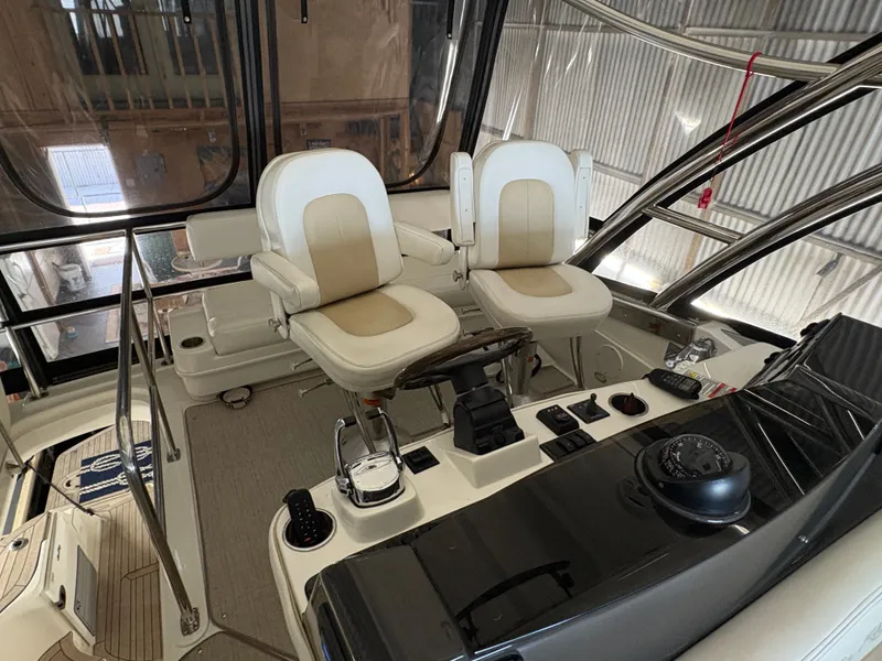 Slide: The Image of The image shows the helm of a 2008 Sea Ray 47 Sedan Bridge with two beige captain's chairs. - 13