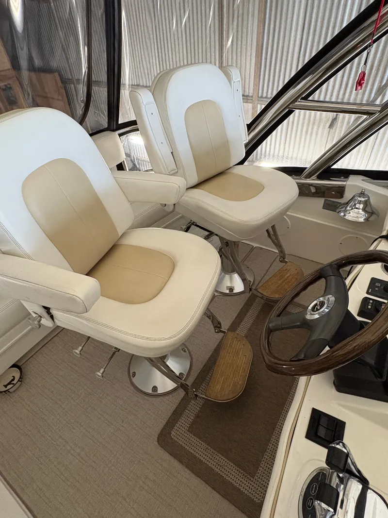Slide: The Image of Two cushioned captain's chairs with armrests and footrests in a boat cockpit. - 15