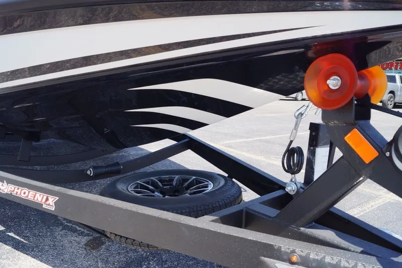Slide: The Image of Trailer for 2027 Phoenix 720 ZXL boat with orange rollers and spare tire. - 2