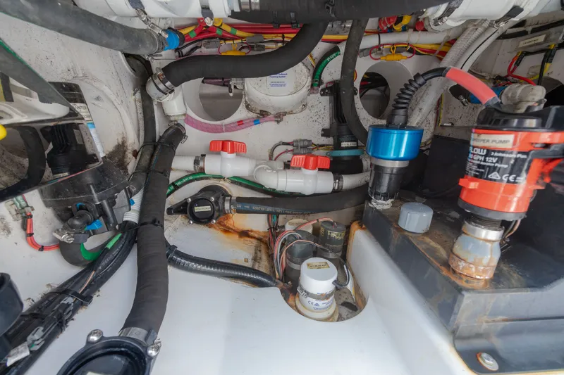 Slide: The Image of View of the engine room in a 2022 Valhalla Boatworks V-37 with various hoses and valves. - 48