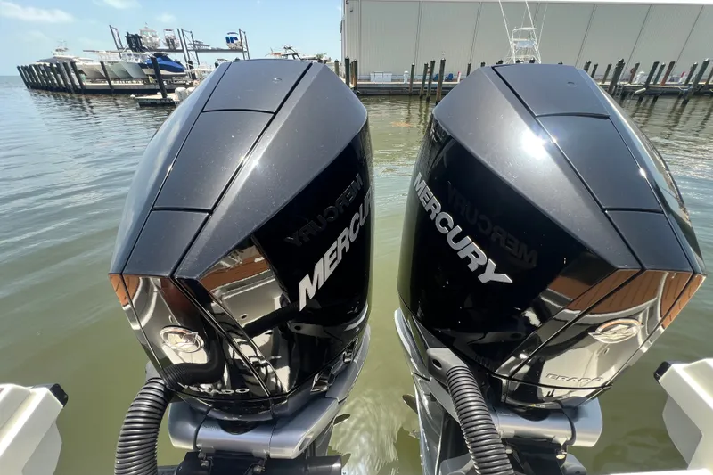 Slide: The Image of Twin Mercury outboard engines on a 2024 Skamander 100 Sorrento boat at a marina. - 66