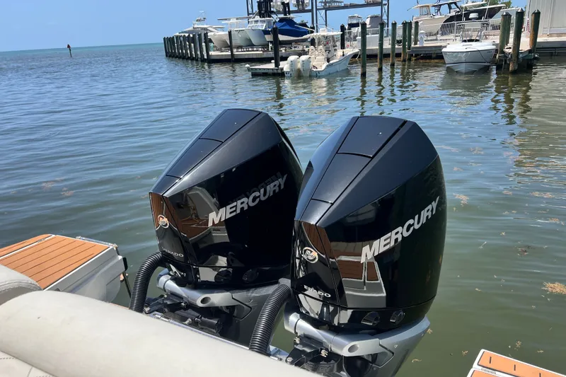 Slide: The Image of Twin Mercury outboard engines on a 2024 Skamander 100 Sorrento boat at a marina. - 63
