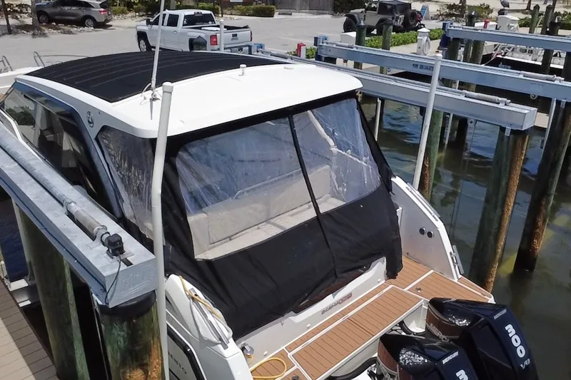 Slide: The Image of 2024 Skamander 100 Sorrento boat docked, featuring a covered deck and twin engines. - 18