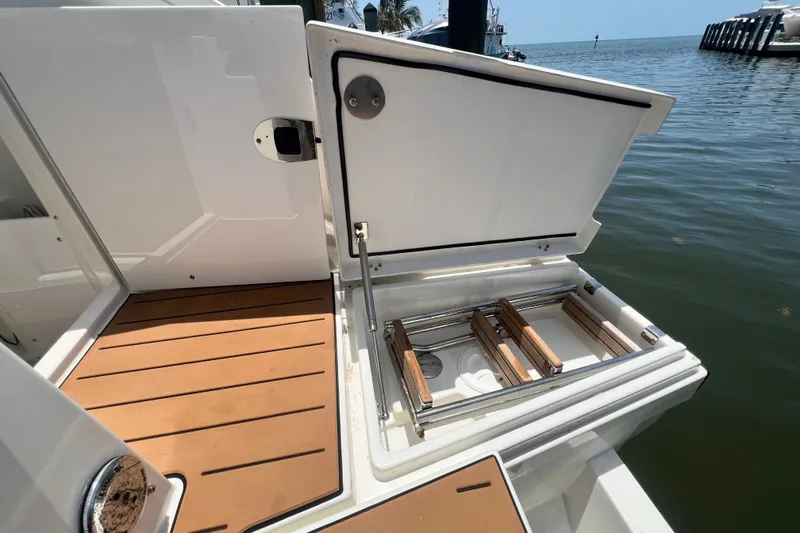 Slide: The Image of 2024 Skamander 100 Sorrento boat with open storage compartment by the water. - 82