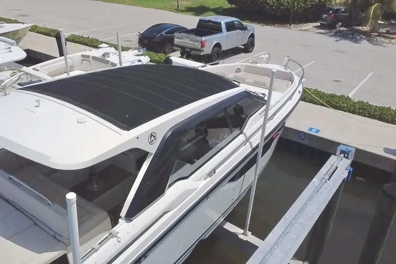 Slide: The Image of 2024 Skamander 100 Sorrento boat docked at marina, with parked vehicles nearby. - 21