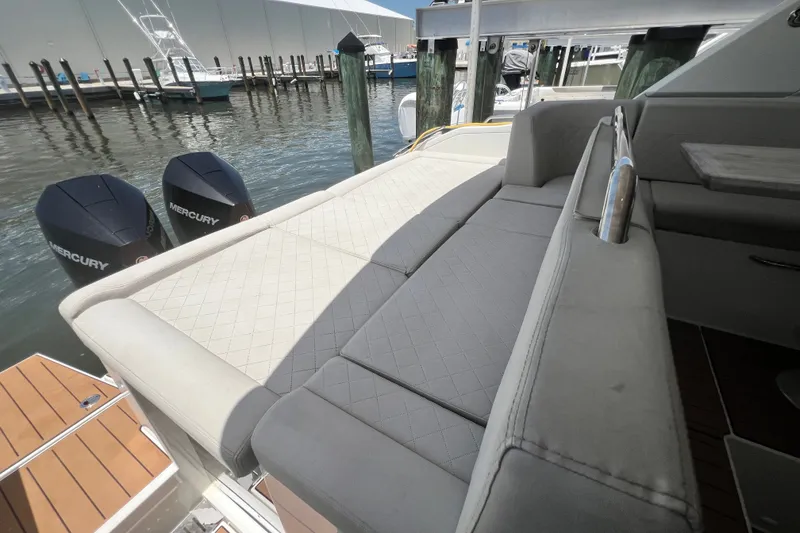 Slide: The Image of 2024 Skamander 100 Sorrento boat with luxurious seating and dual Mercury engines at a marina. - 84