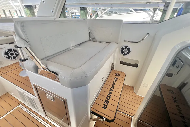 Slide: The Image of 2024 Skamander 100 Sorrento boat interior with cushioned seating and teak flooring. - 117