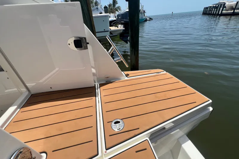 Slide: The Image of 2024 Skamander 100 Sorrento boat deck by the water, featuring sleek wooden finish. - 77