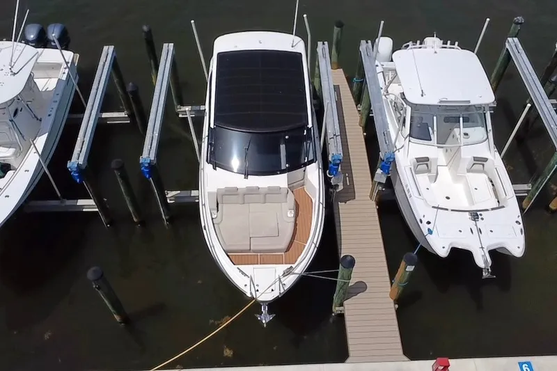 Slide: The Image of 2024 Skamander 100 Sorrento boat docked between two other boats at a marina. - 2