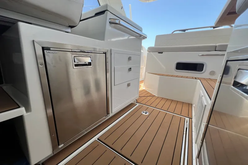 Slide: The Image of 2024 Skamander 100 Sorrento boat interior with teak flooring and stainless steel fridge. - 168