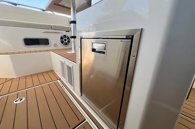 Slide: The Image of 2024 Skamander 100 Sorrento boat interior with stainless steel fridge and teak flooring. - 169