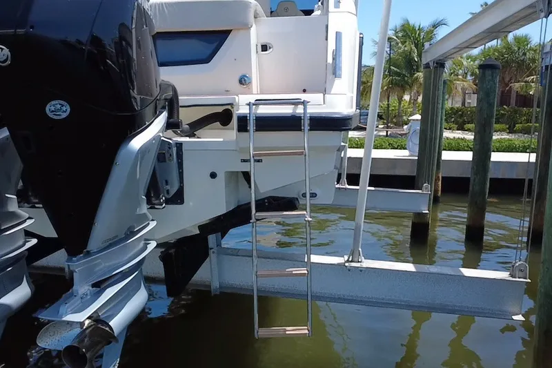 Slide: The Image of 2024 Skamander 100 Sorrento boat with ladder and outboard motor in marina setting. - 5