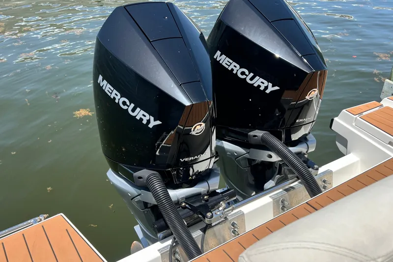 Slide: The Image of Twin Mercury outboard engines on a 2024 Skamander 100 Sorrento boat, docked on water. - 61