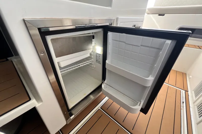 Slide: The Image of Open refrigerator on 2024 Skamander 100 Sorrento boat, showcasing interior storage space. - 171