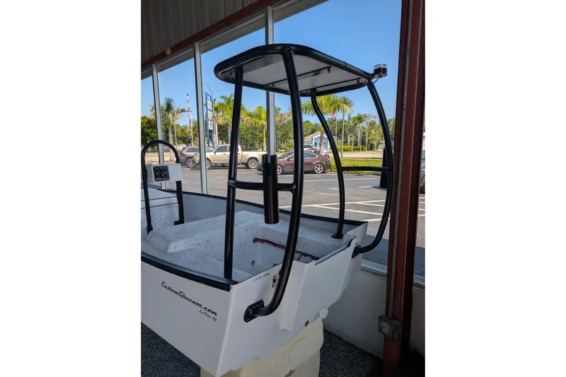 Slide: The Image of 2026 Gheenoe Lo Tide 25 boat with T-top, parked indoors. - 1