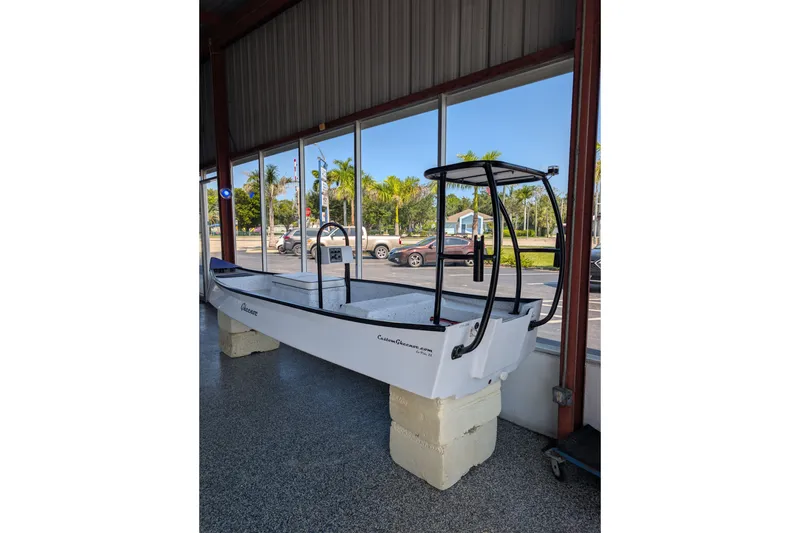 The Image of 2026 Gheenoe Lo Tide 25 boat displayed indoors with large windows and palm trees outside. - 0