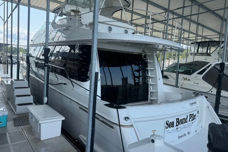 The Image of 2003 Carver 570 Voyager Pilothouse yacht docked in a marina under a covered structure. - 9