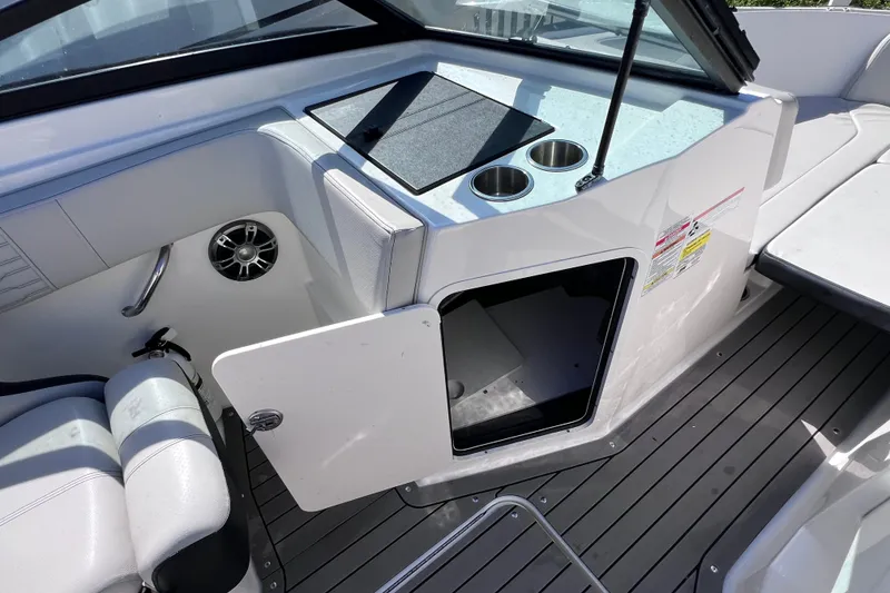 Slide: The Image of 2022 Sea Ray SPX 210 Outboard boat interior with open storage compartment and cup holders. - 24