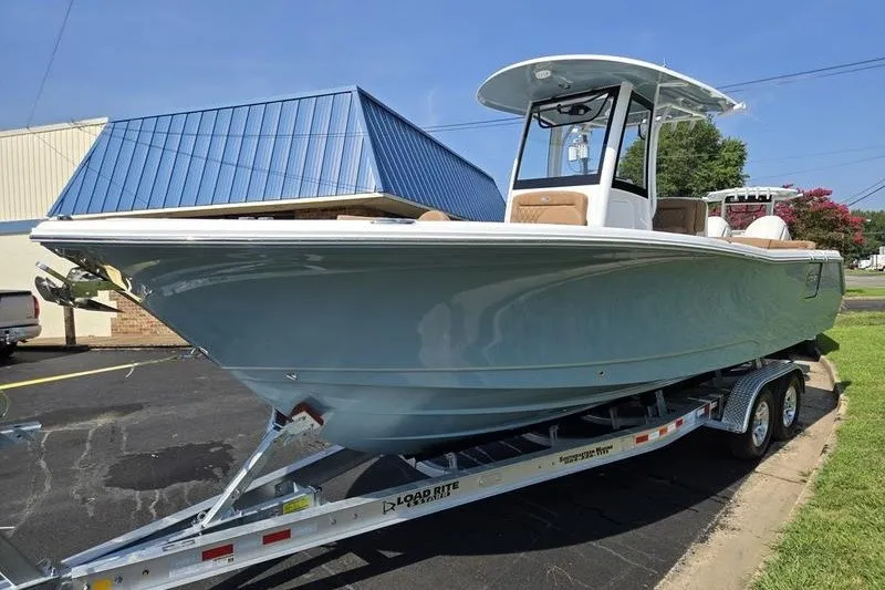 Slide: The Image of 2027 Sea Hunt Ultra 275SE boat on trailer, parked outdoors near a blue-roofed building. - 7