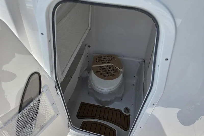 Slide: The Image of Sea Hunt Ultra 275SE 2027 boat compartment with portable toilet and wooden flooring. - 5