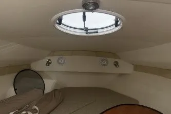 Slide: The Image of 2006 Larson Cabrio 260 cabin interior with circular window and cozy sleeping area. - 25