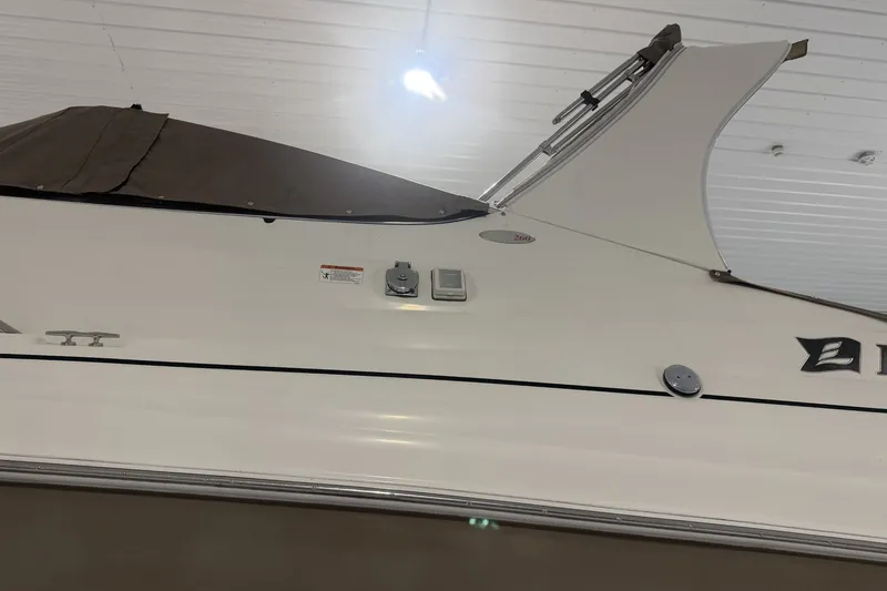 Slide: The Image of 2006 Larson Cabrio 260 boat side view with covered top in indoor storage. - 7