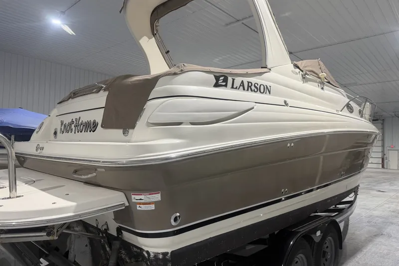 The Image of 2006 Larson Cabrio 260 boat in indoor storage, featuring sleek design and "Knot Home" name. - 1