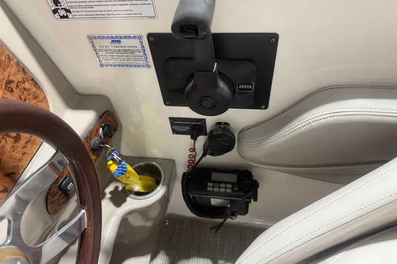 Slide: The Image of 2006 Larson Cabrio 260 boat cockpit with steering wheel, controls, and certification label. - 16