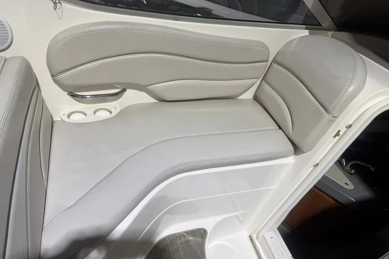 Slide: The Image of Interior seating of a 2006 Larson Cabrio 260 boat, featuring gray upholstery and cup holders. - 14