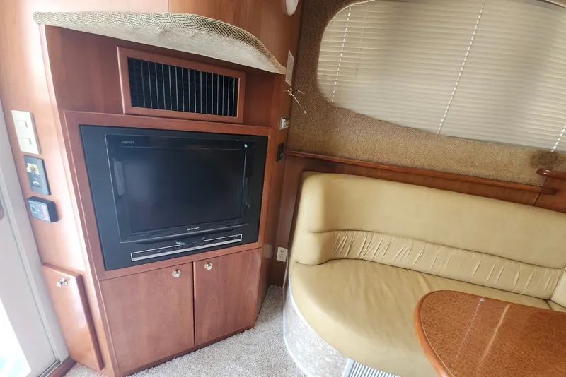Slide: The Image of Interior of 2008 Silverton 36 Convertible yacht with TV and beige seating area. - 28