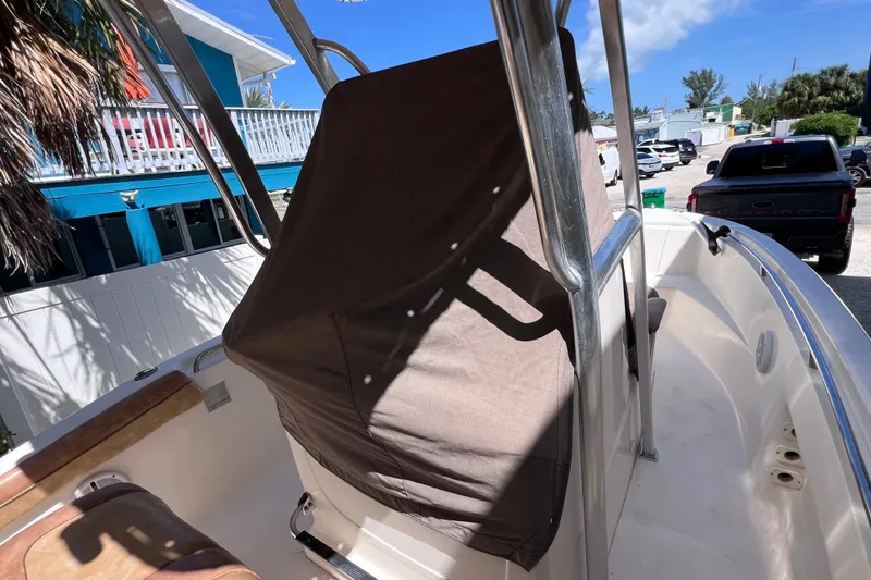Slide: The Image of 2012 Scout 210 XSF boat interior with covered console, parked near colorful buildings. - 21