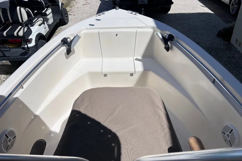 Slide: The Image of 2012 Scout 210 XSF boat interior with seating and speakers, parked near a golf cart. - 36