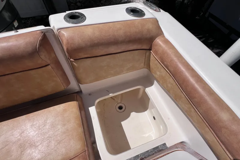 Slide: The Image of Interior seating of a 2012 Scout 210 XSF boat with tan upholstery and storage compartment. - 18